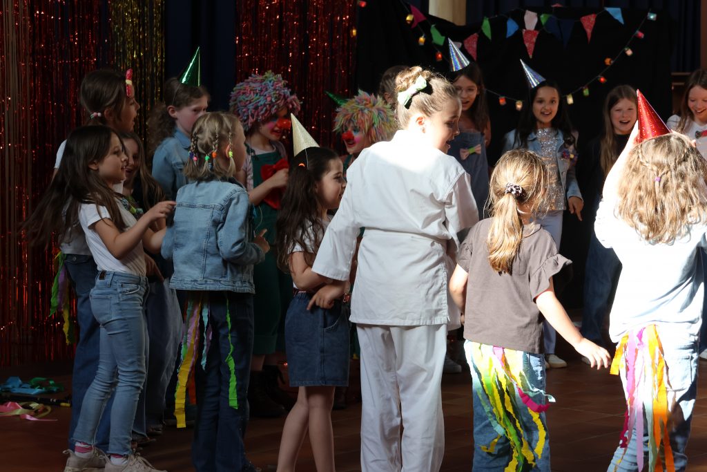 Der Kinderchor und der Nachwuchschor stehen auf der Bühne. Sie haben Zirkus-Kostüme an.